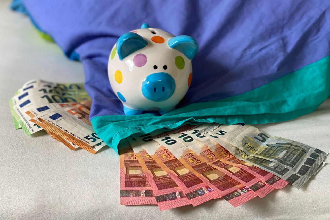 Sparschwein mit Geldscheinen unter dem Kopfkissen