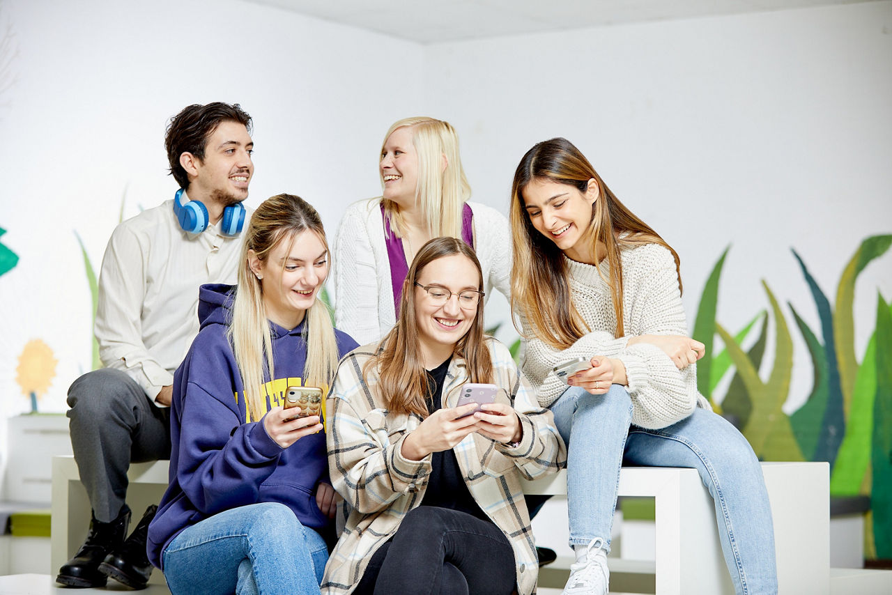 Gruppe junger Menschen, zum Teil mit Handy in der Hand
