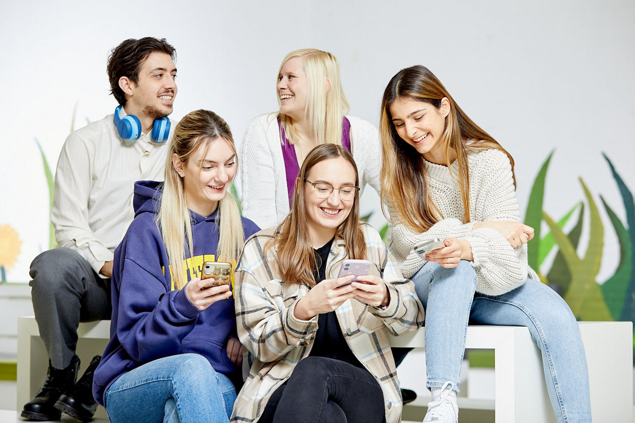 Gruppe junger Menschen, zum Teil mit Handy in der Hand