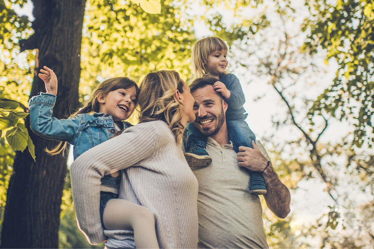 Eine Familie steht lächelnd in der Natur
