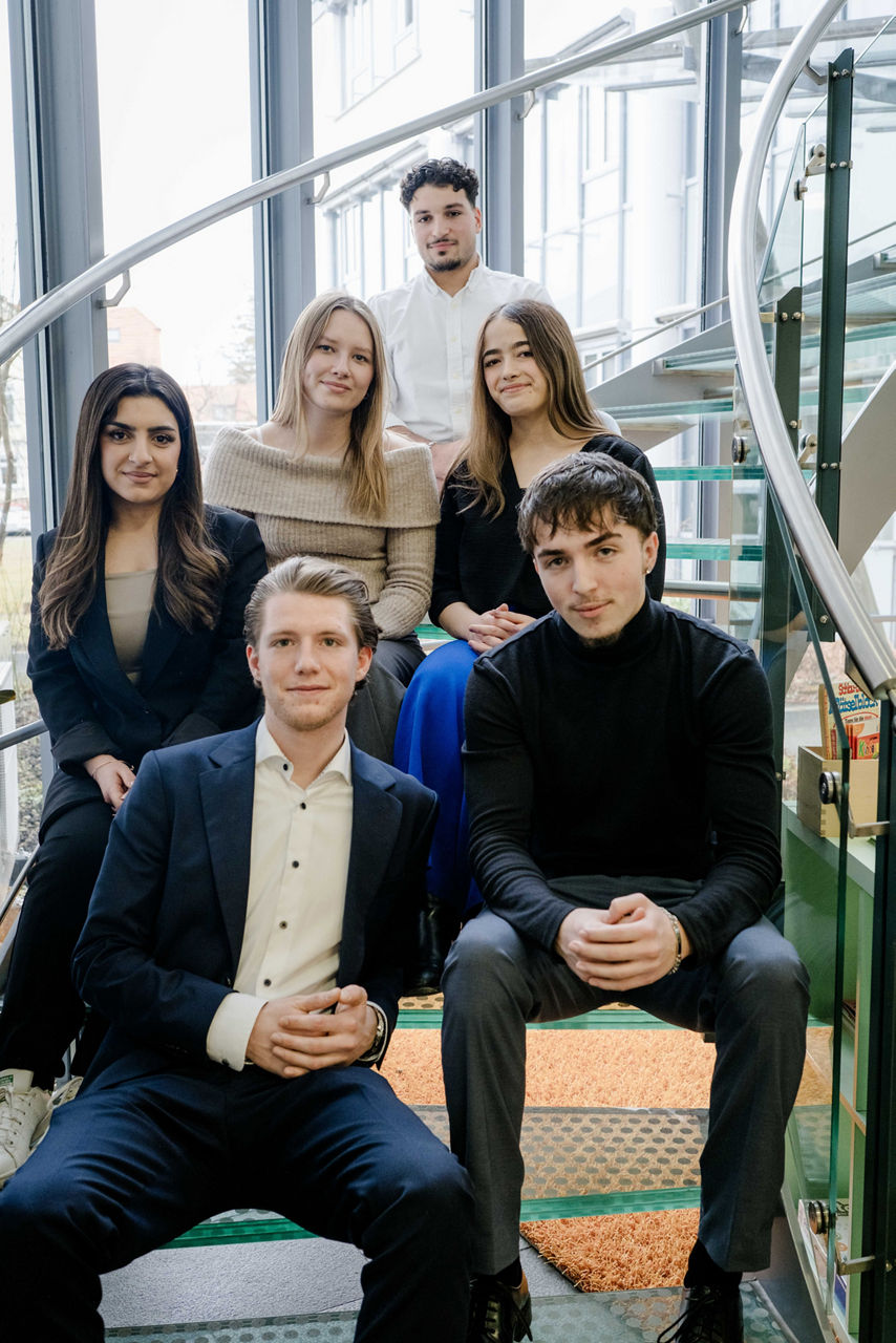 Unsere Auszubildenden sitzen für ein gemeinsames Foto als Team auf der Treppe