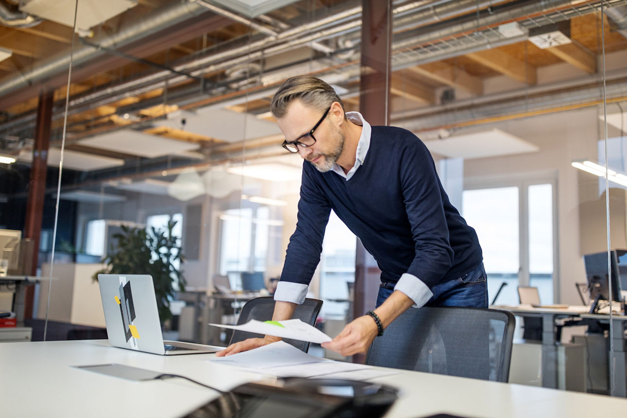 Ein Mann schaut im Büro auf Unterlagen