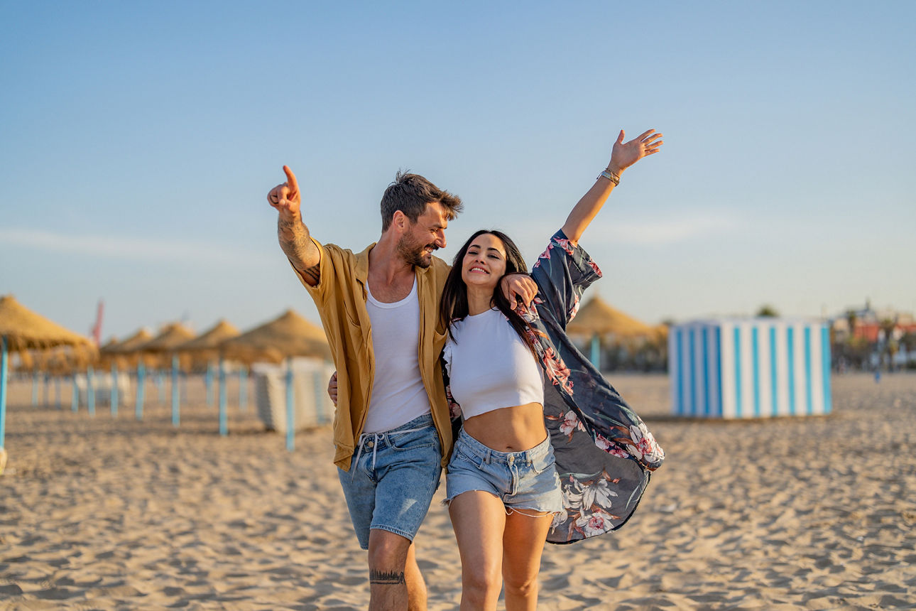 Ein Paar hält sich im Arm am Strand und strahlt vor Freude