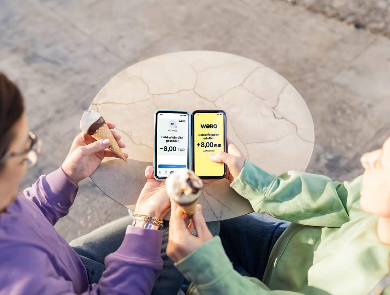 Zwei Menschen zeigen ihre Smartphones, wie sie Eis-Schulden mit Wero schnell & sicher begleichen