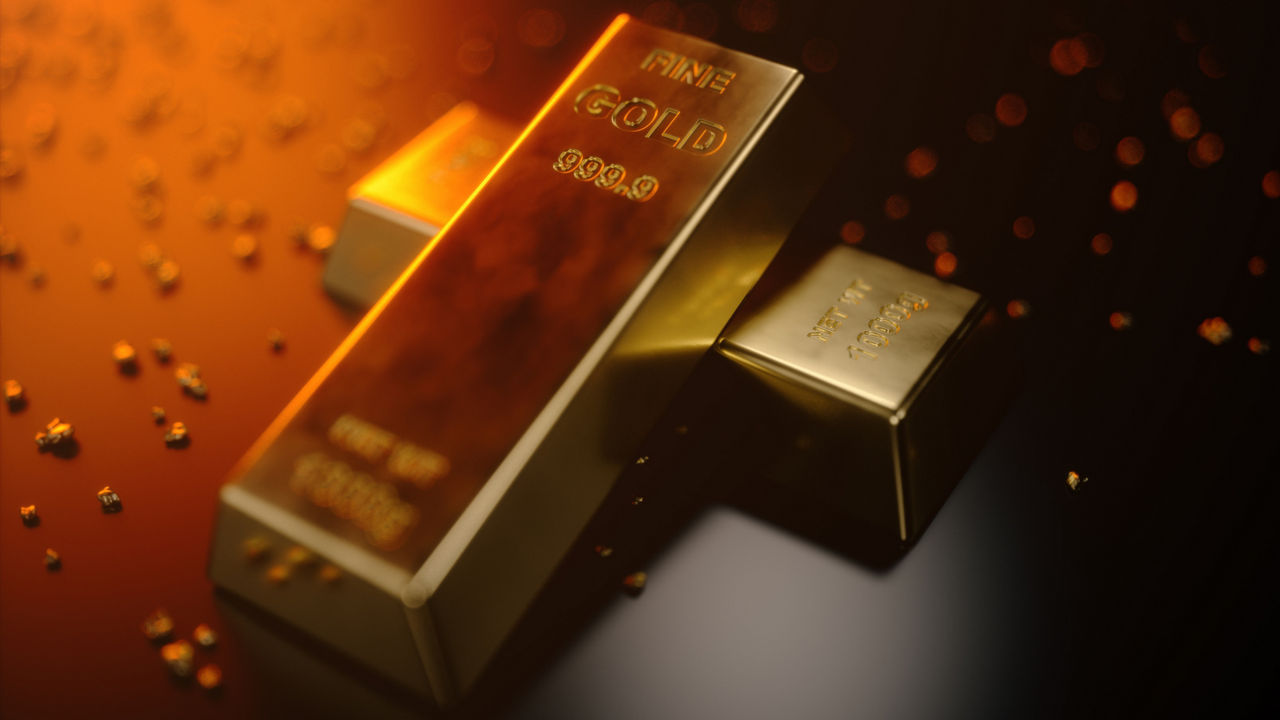 Zwei Goldbarren liegen versetzt übereinander auf einem dunklen Untergrund. 