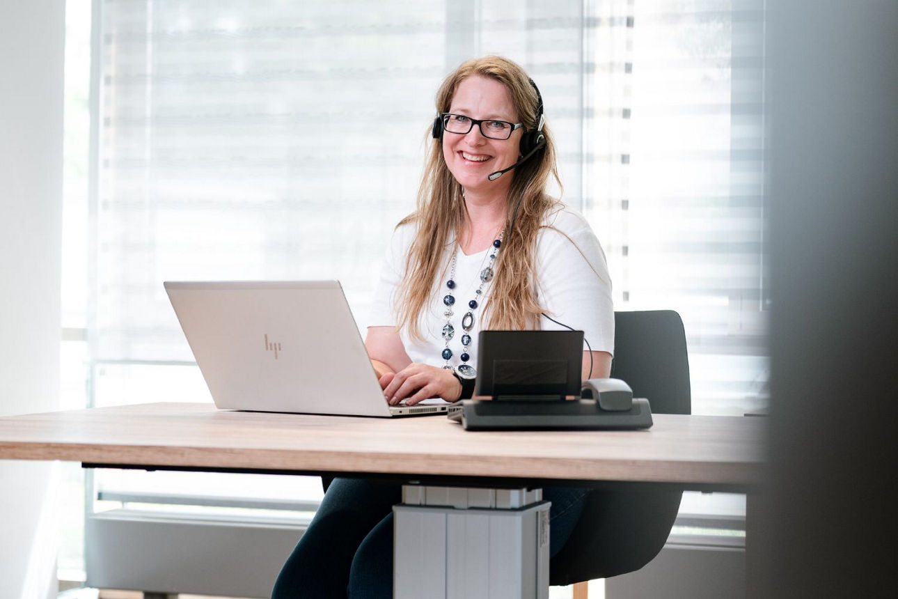 Frau sitzt mit Laptop am Schreibtisch