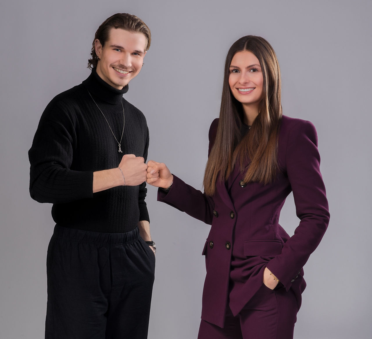 Ein junger Mann und eine junge Frau lachen in die Kamera und halten die Fäuste aneinander.