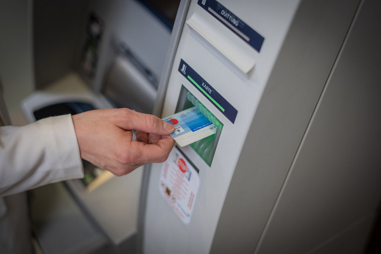 Eine Frau steckt ihre Bankkarte in einen Geldautomaten