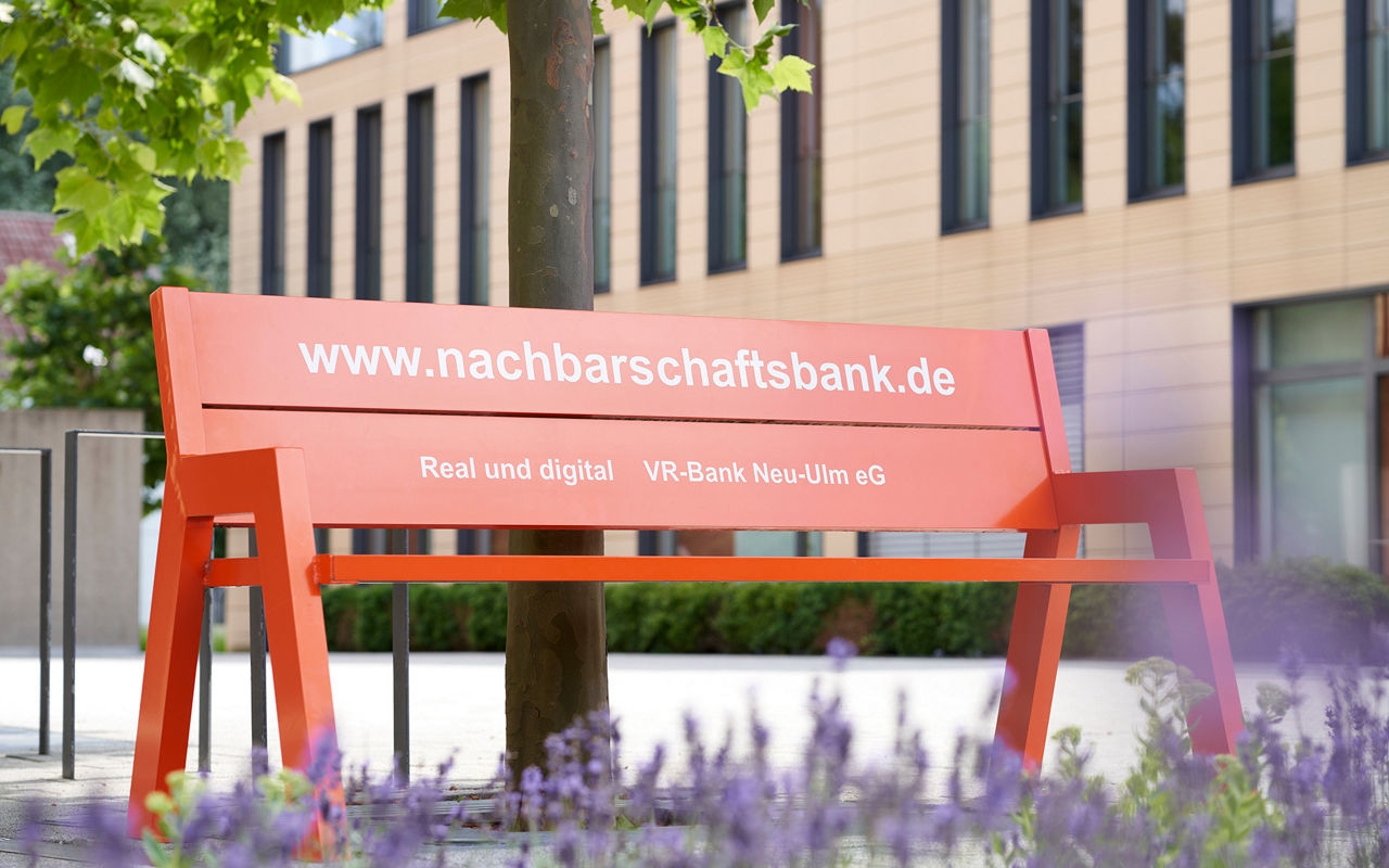 Orange Nachbarschaftsbank vor Baum