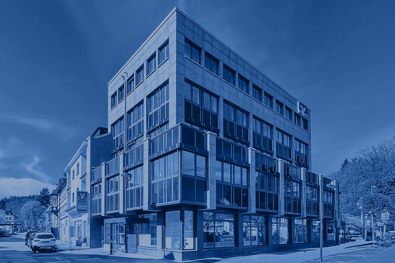 Modernes Bankgebäude an einer Straßenecke mit großen Glasfronten und markantem Fassadendesign, im Stadtzentrum gelegen.