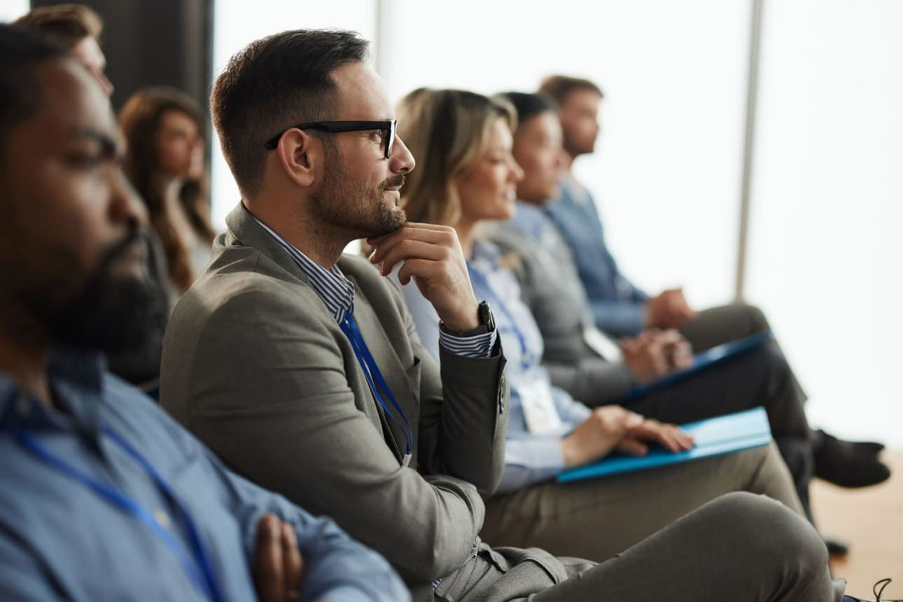 Mehrere Menschen sitzen in einem Vortrag und hören interessiert zu