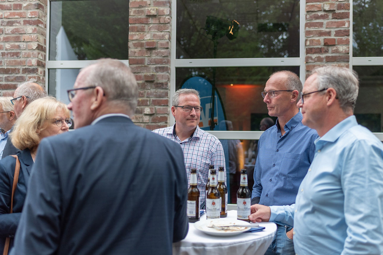 Gespräche vor Beginn der Vertreterversammlung der Gäste an einem Stehtisch.