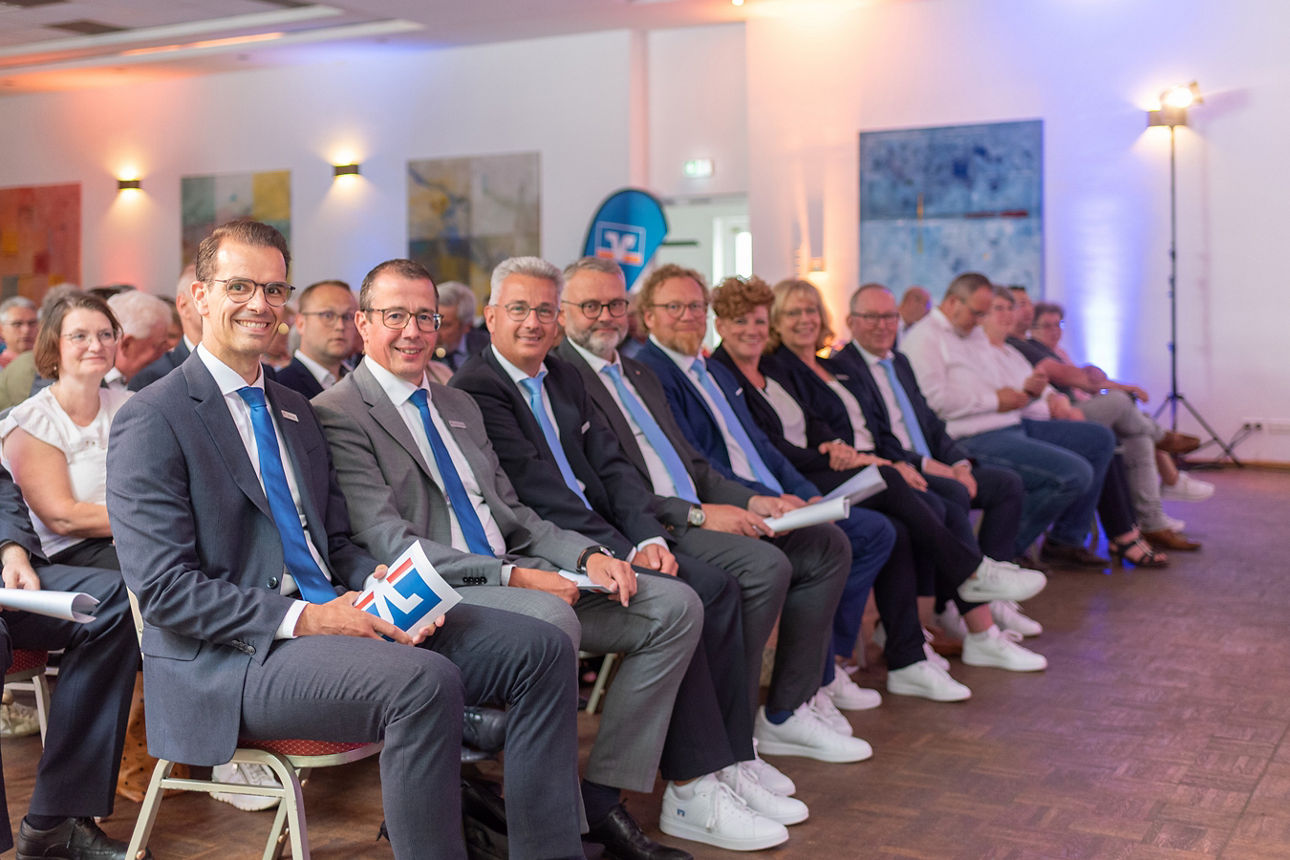 Aufsichtrat sitz in einer Reihe und schaut in die Kamera.