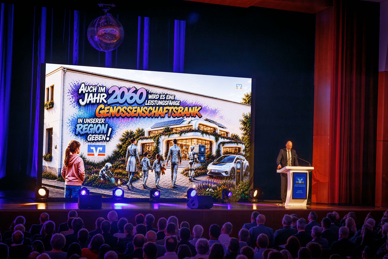 Eine große Leinwand mit Präsentation der VR-Bank auf der Bühne
