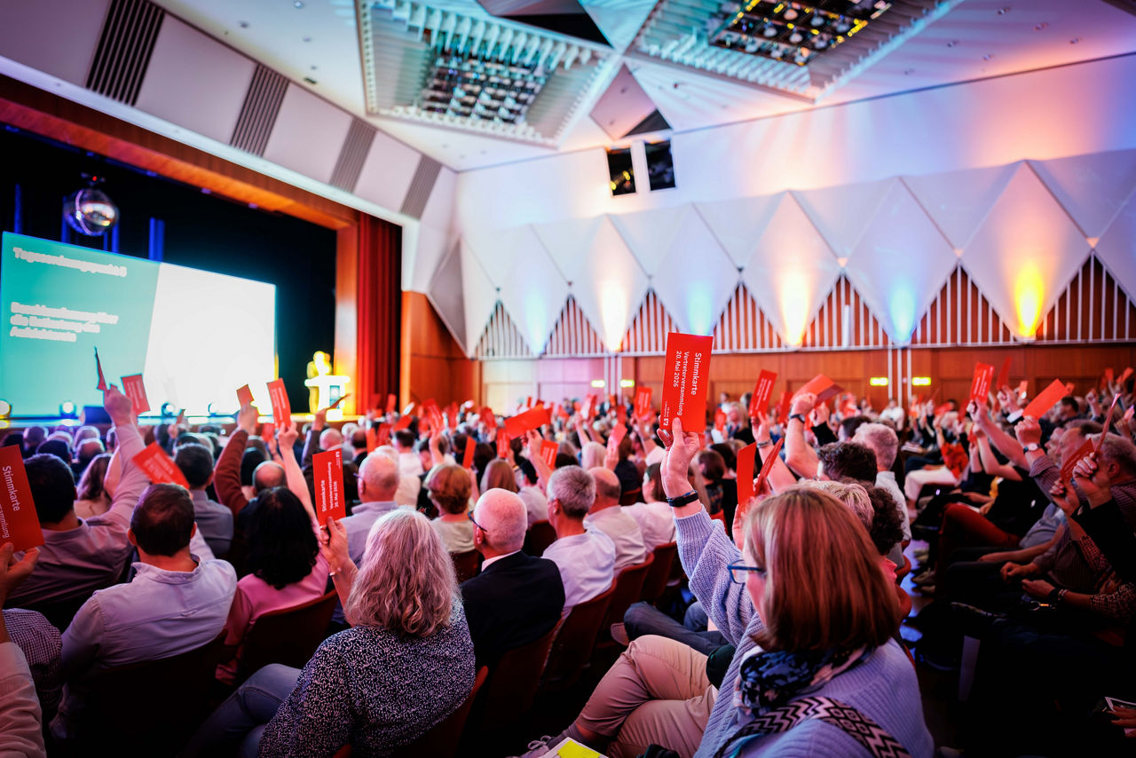 Blick in einen großen Saal wo Vertreterinnen und Vertreter der Bank gerade abstimmen