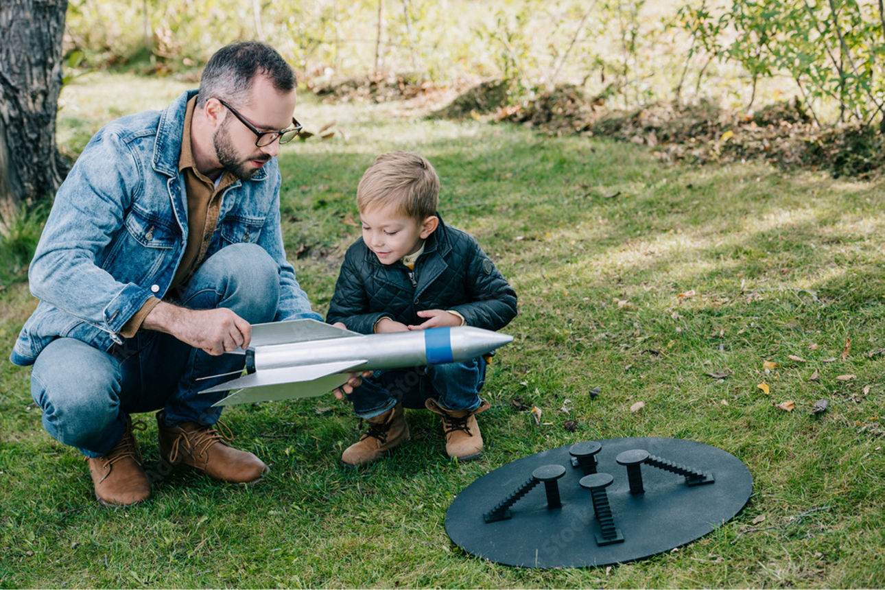 Vater und Sohn in einem Park mit einer Rakete in der Hand.