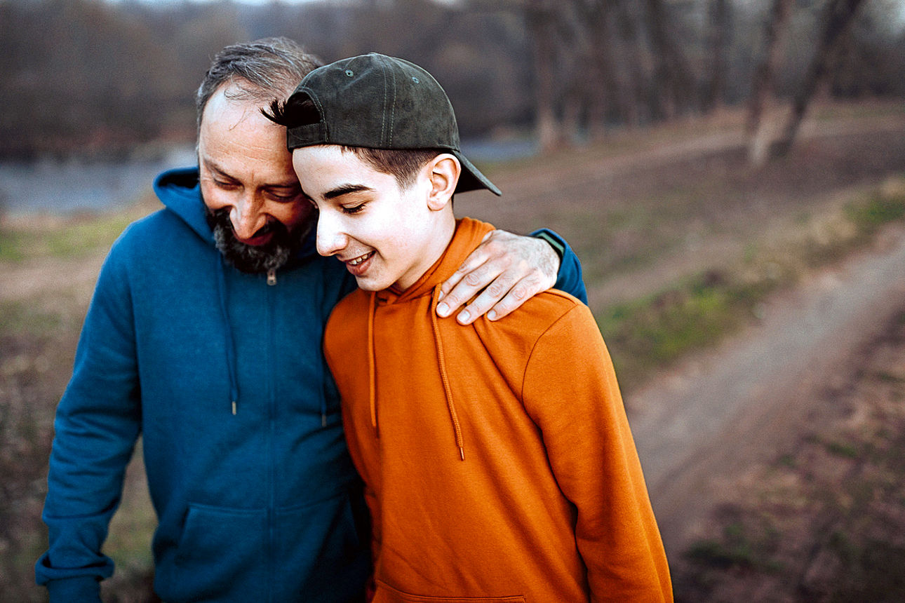 Vater und Sohn gehen lachend zusammen spazieren.