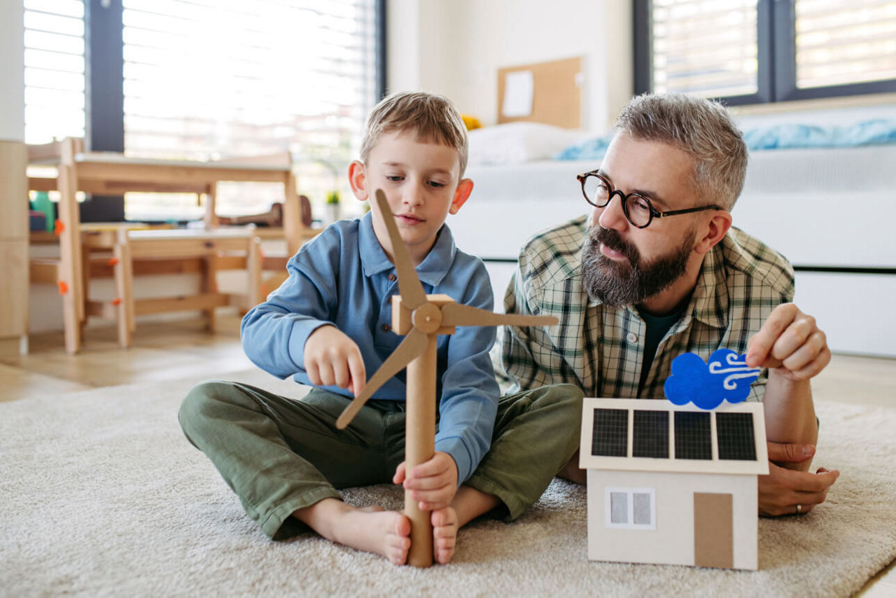 Vater und Sohn spielen mit einem Haus mit Photovoltaik