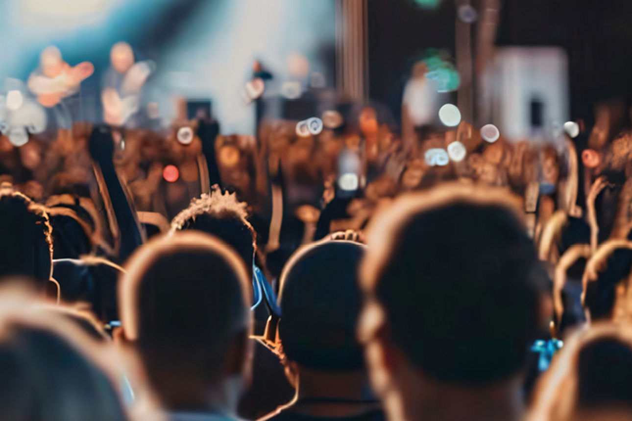 Menschenmenge vor einer Bühne bei einem Konzert mit erhobenen Händen