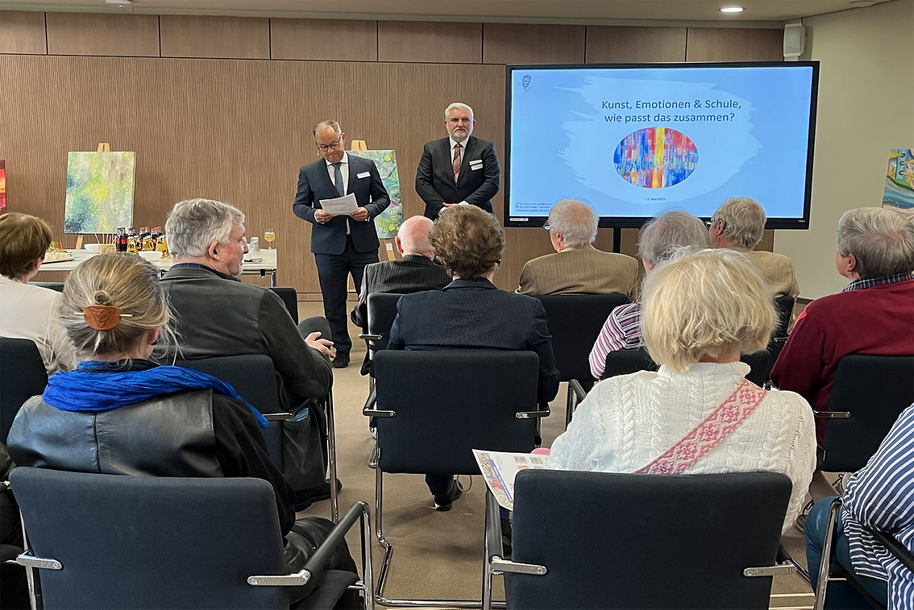 Impressionen der Veranstaltung - Blick  auf das Podium mit zwei Sprechern