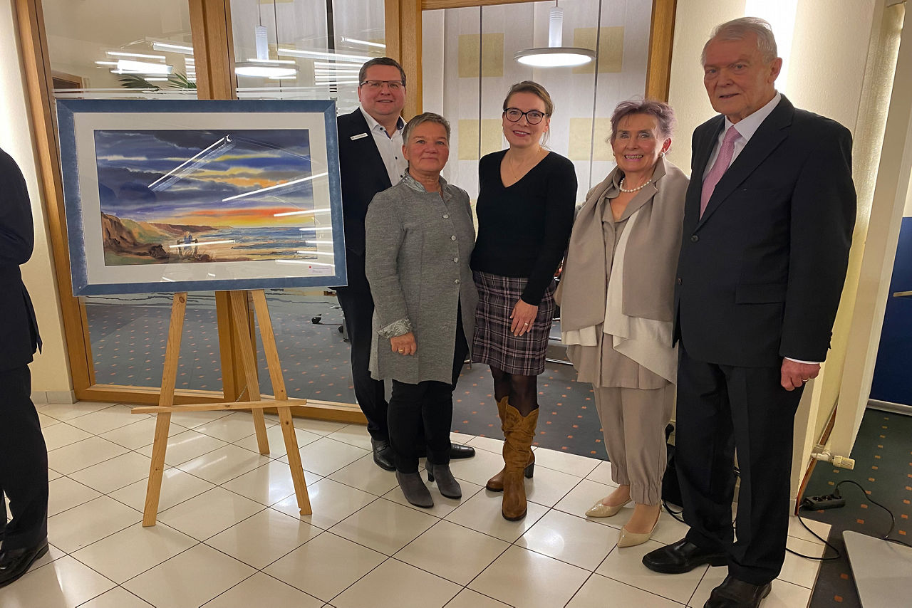 Vernissage Träumerei mit Wolken - mehrer Personen stehen bei einer Staffelei mit Bild