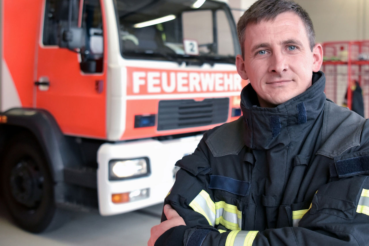 Ein Feuerwehrmann steht vor einem Feuerwehrauto