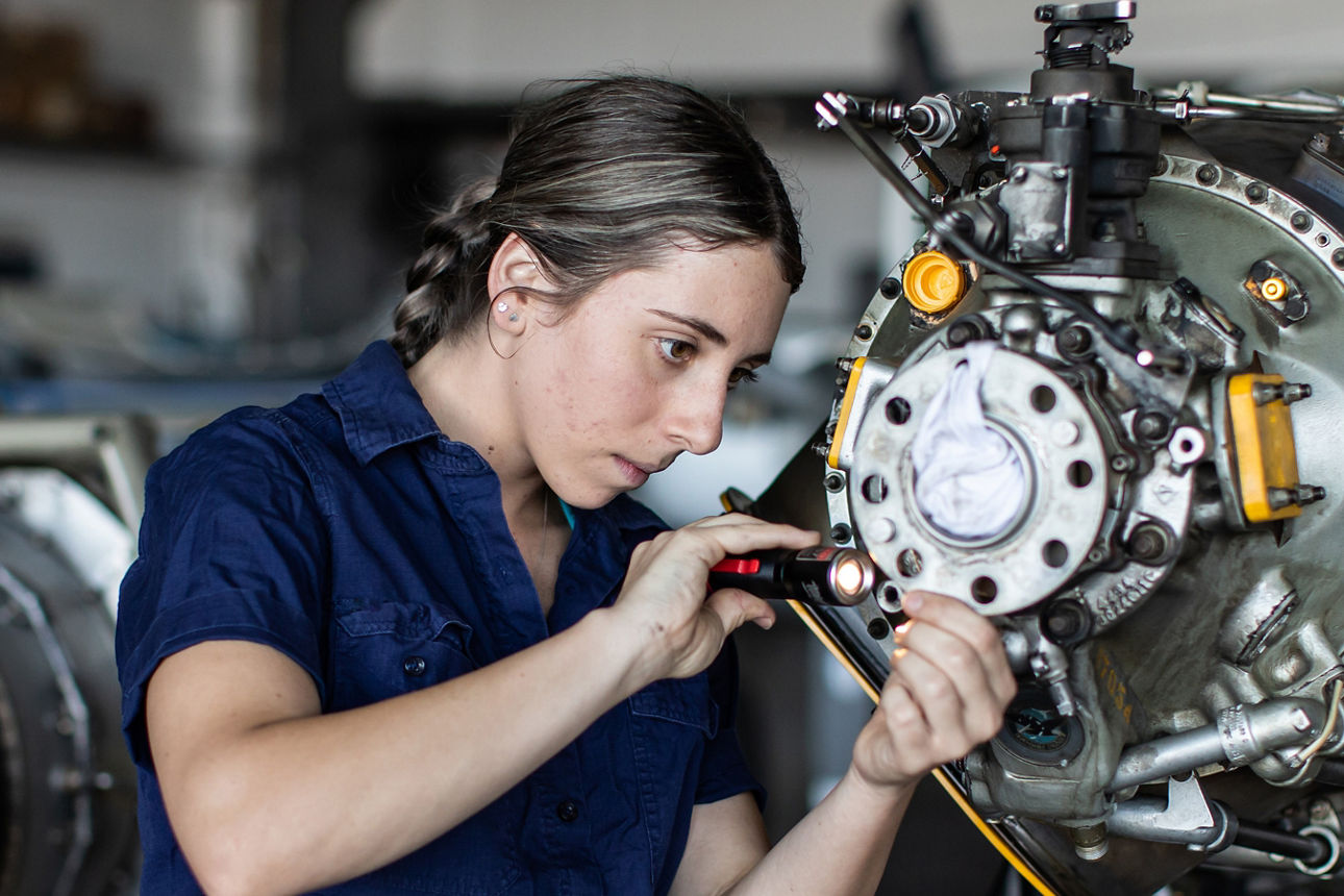 Anzeige Vereine allgemein 5 - Eine junge Mechanikerin untersucht einen Motor mit der Taschenlampe
