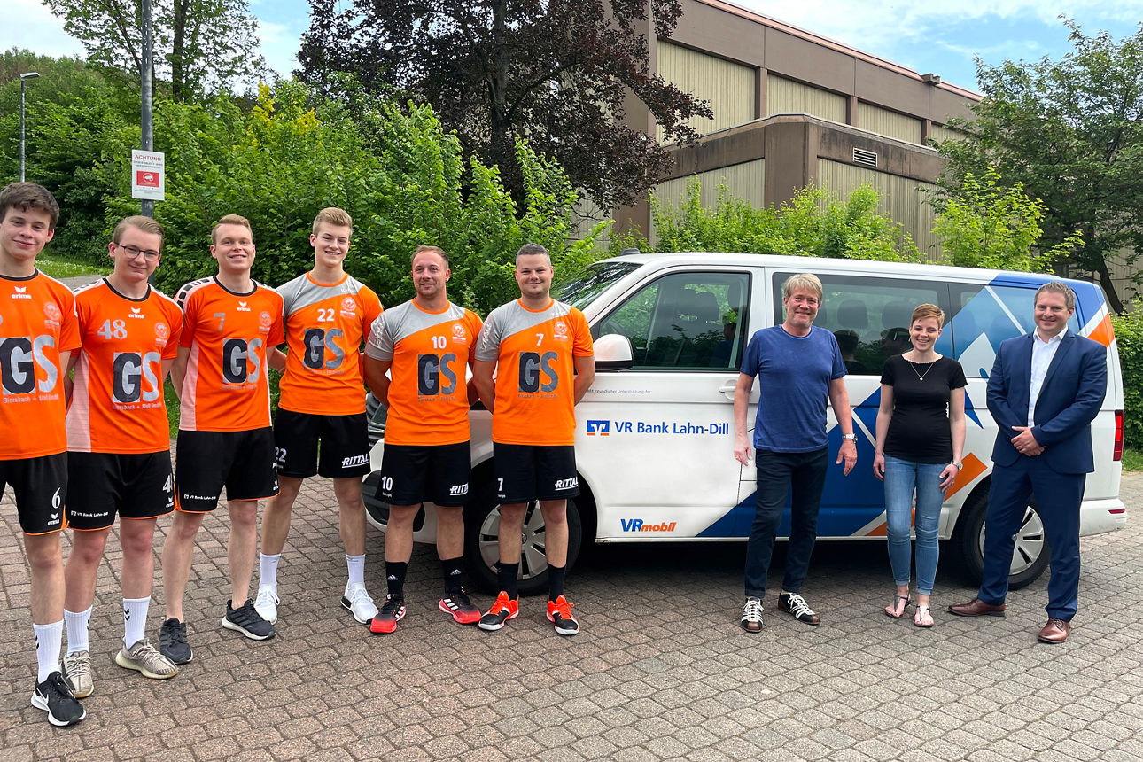 Vor einem Bus steht eine Handballmannschaft nach der Spendenübergabe