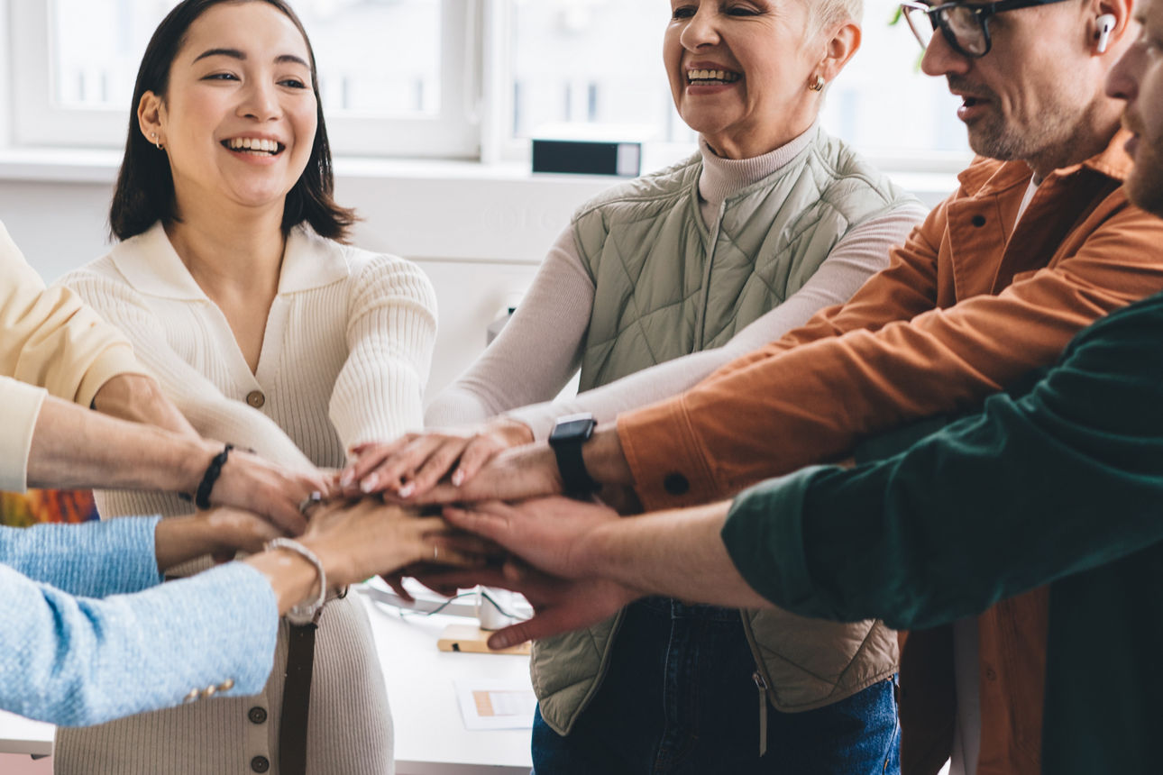 Gruppe von Menschen steht im Kreis und legt ihre Hände übereinander