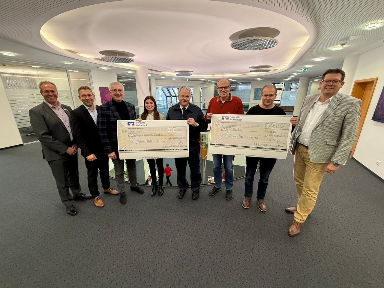 Spendenübergabe mit zwei großen Spendenschecks in der Vereinten Volksbank