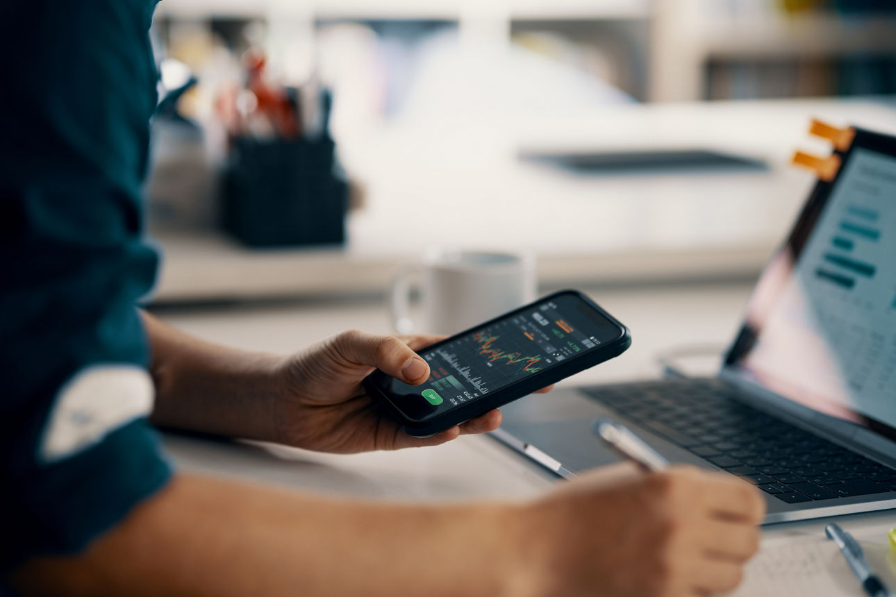 Person hält ein Handy in den Händen und verfolgt Aktienkurse