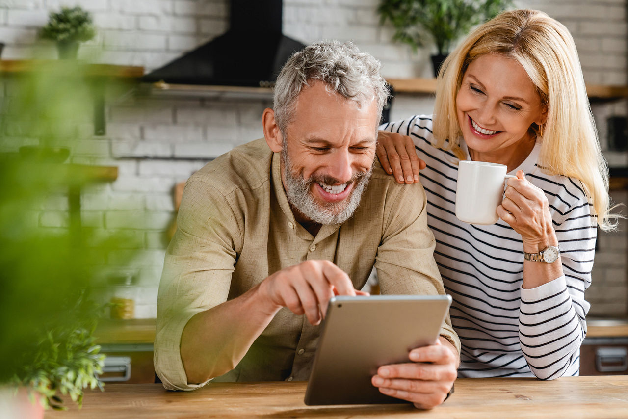 Fröhliches Ehepaar mit Tasse und Tablet