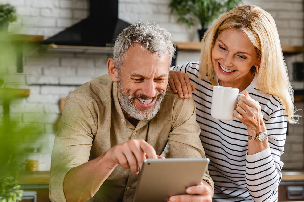 Fröhliches Ehepaar mit Tasse und Tablet