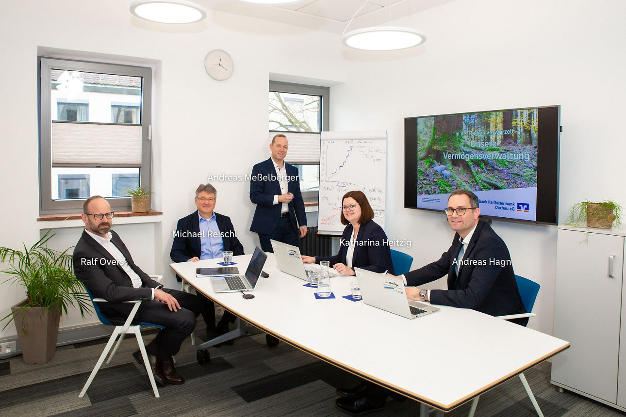Eine Frau und ein vier Männer sitzen im Büro in einer Besprechung