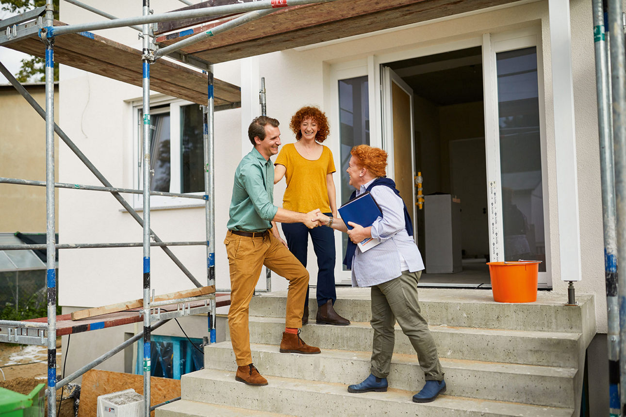 3 Personen, die vor einem Haus stehen, das gerade renoviert wird.