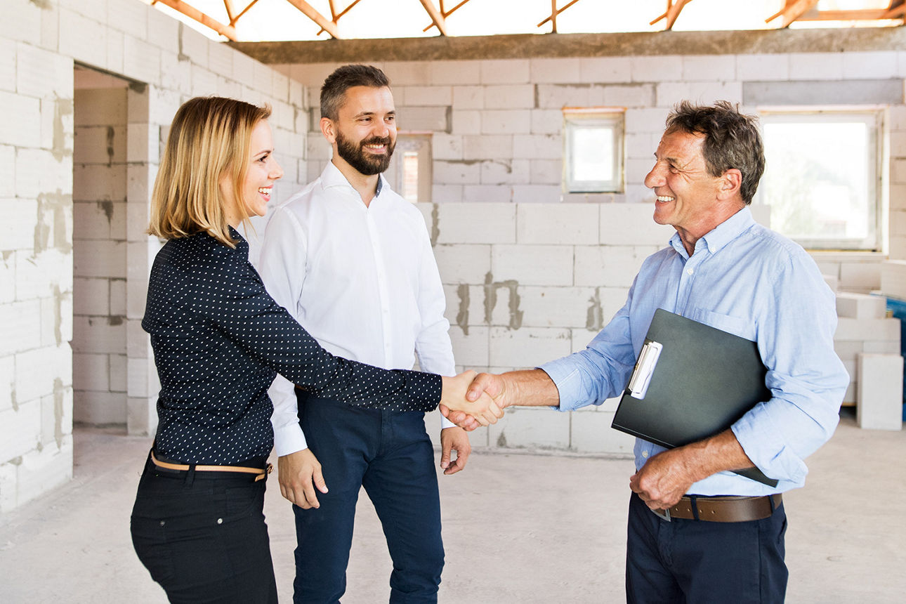 zwei Personen in einem Rohbau schütteln die Hände