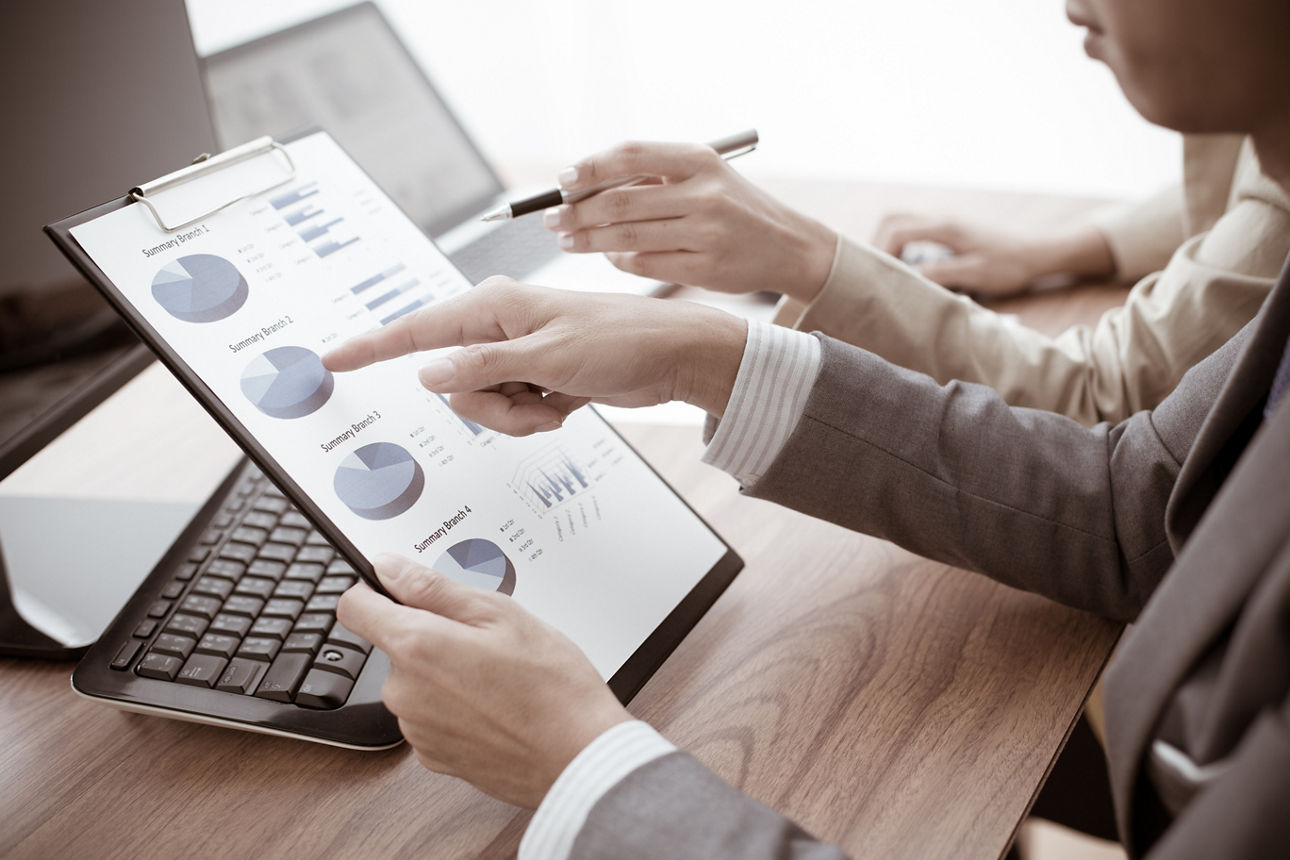 Zwei Hände zeigen auf eine Tablet. Auf dem Bildschirm sind bunte Grafiken zu sehen.