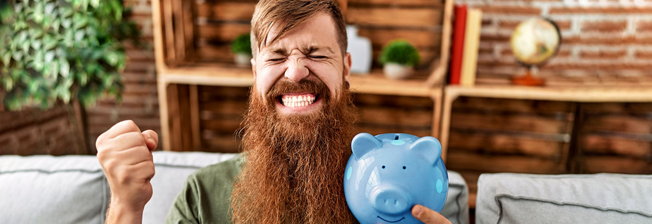 Fröhlicher Hipster hält Sparschwein in der Hand.