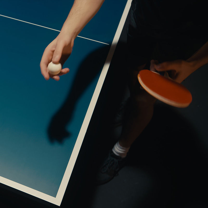 Eine Hand mit Tischtennisch Ball und eine mit Schläger