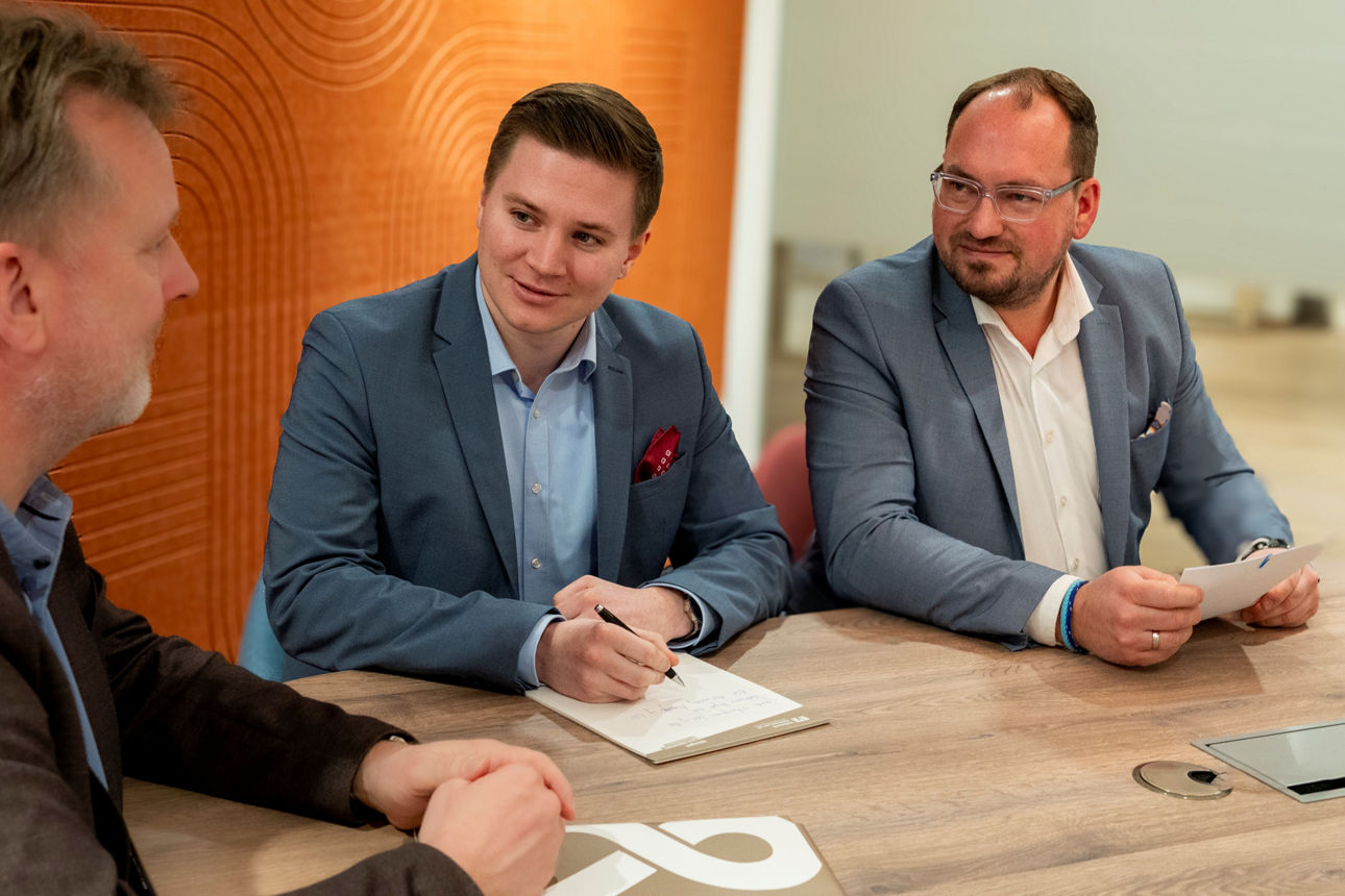 Ein Berater führt ein Gespräch mit zwei Kunden an einem Tisch