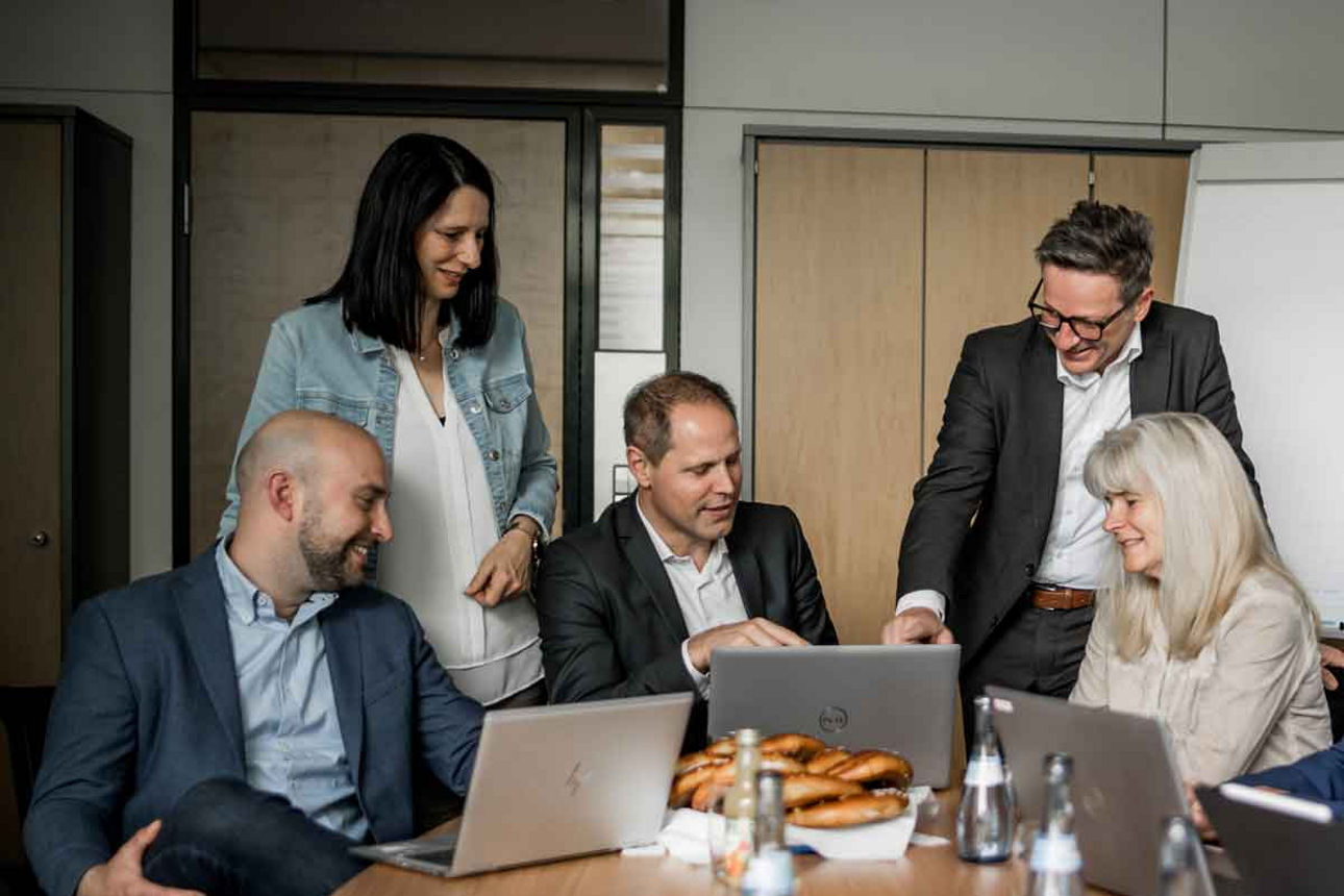 Mitarbeiterinenn und Mitarbeiter von Versichtert@Volksbank an einem Besprechungstisch