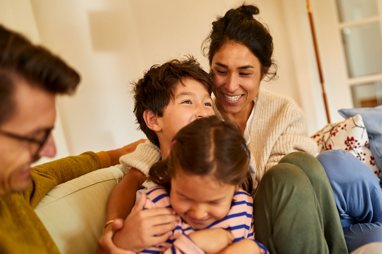 Eine vierköpfige Familie sitzten zusammen auf einem Sofa.