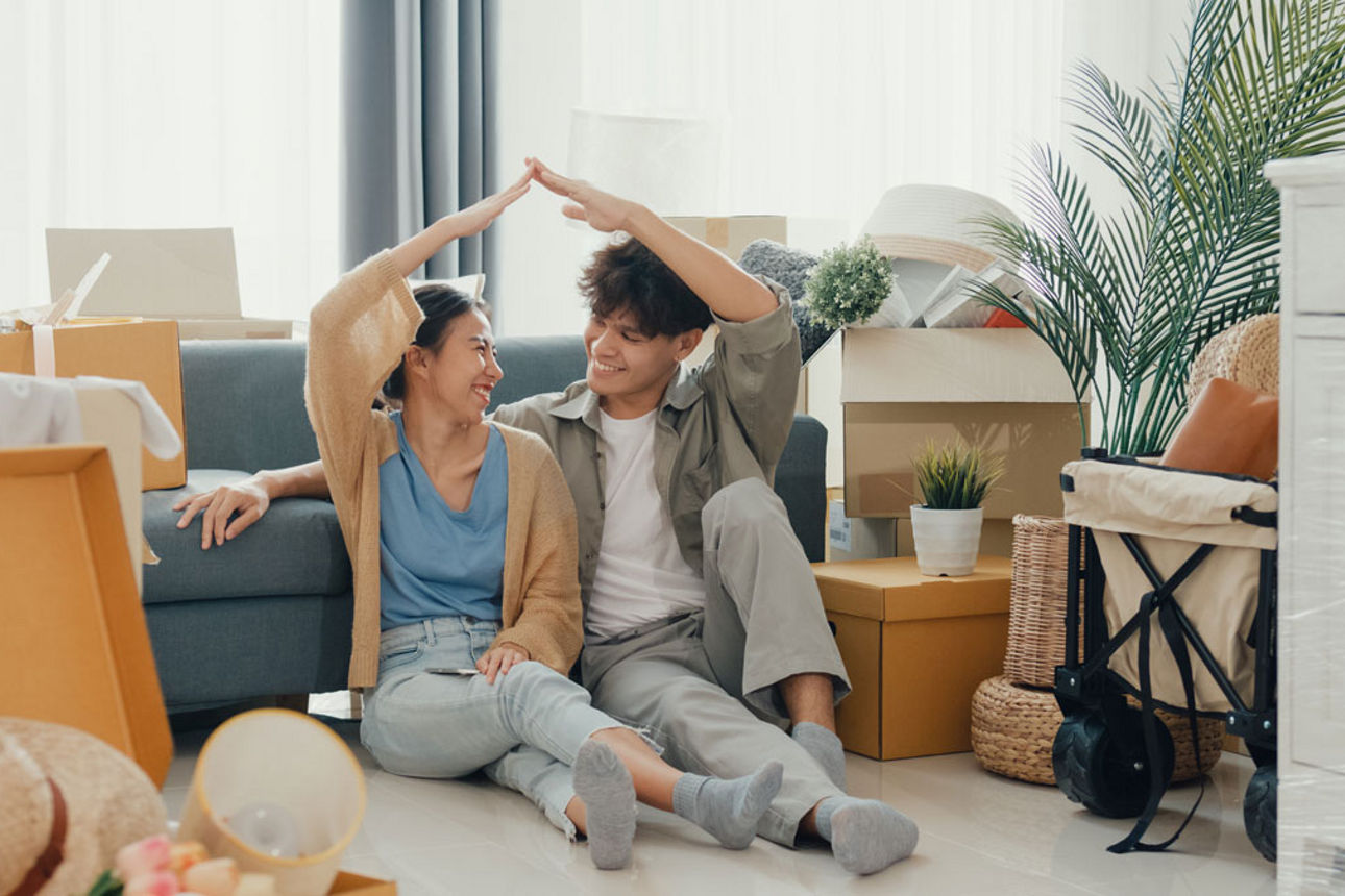Junges Pärchen sitzt frustriert im Wohnzimmer, in der Decke ist ein Leck
