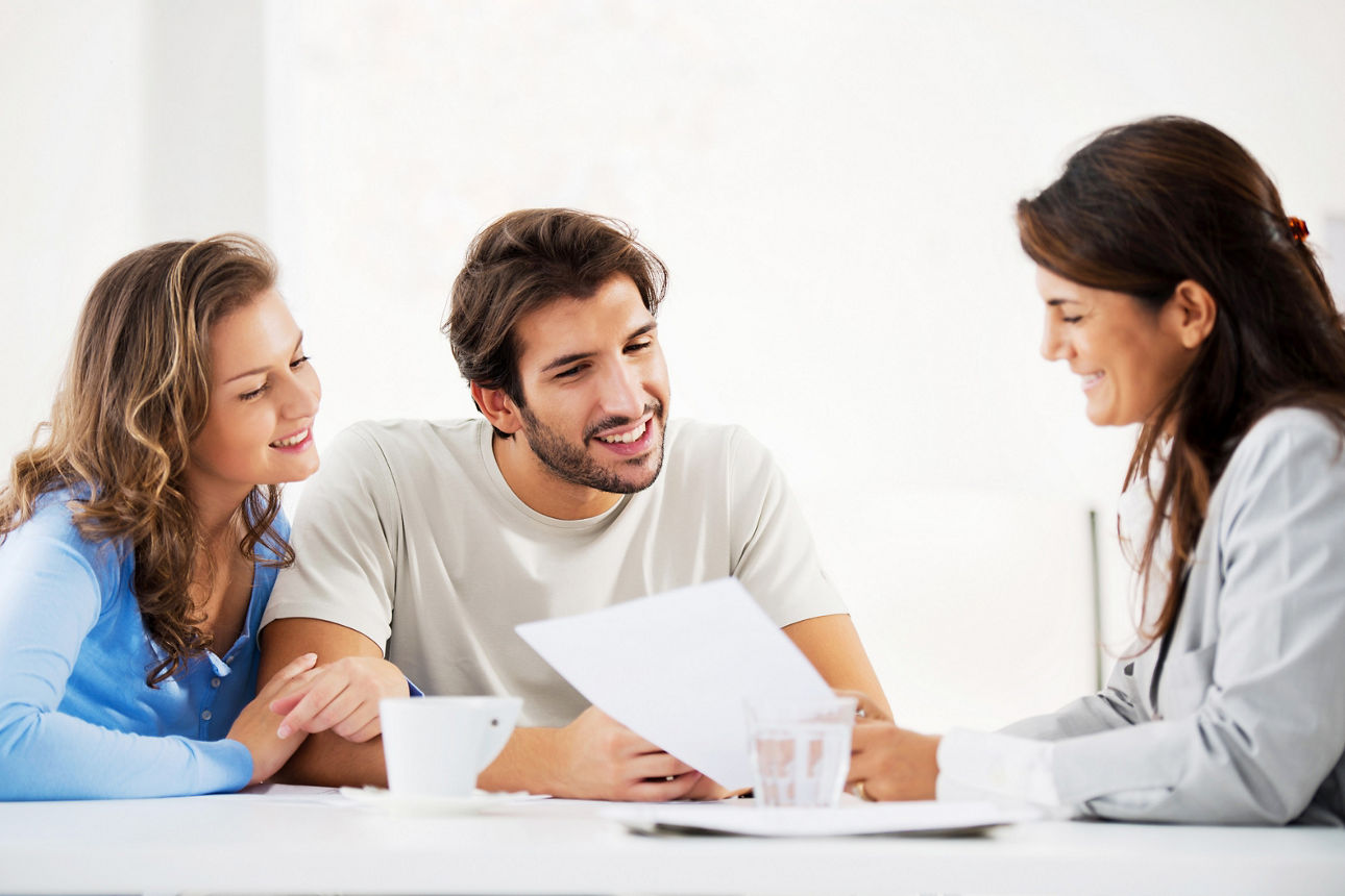 Lächelndes Paar in Gespräch mit Versicherungsberaterin