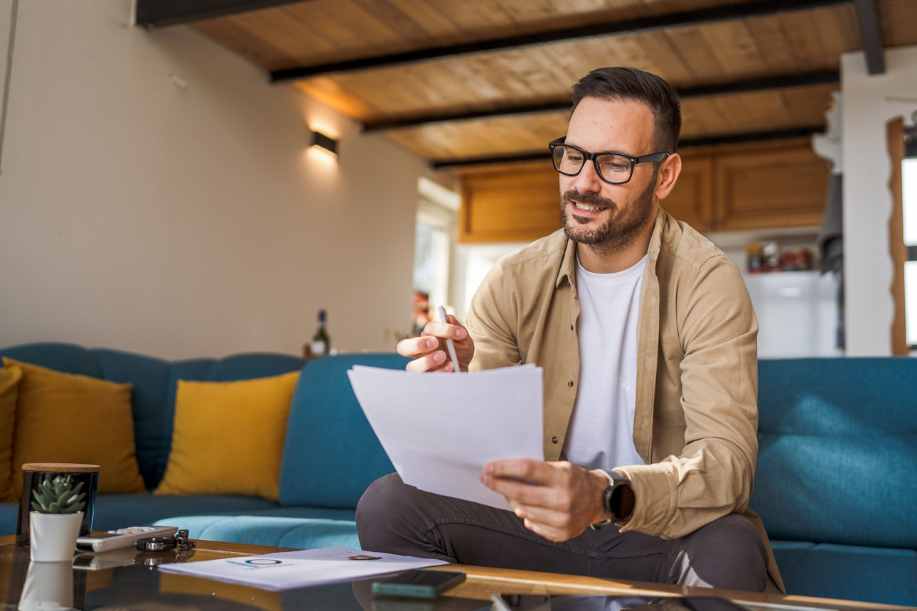 Mann sitzt auf dem Sofa und schaut sich seine Versicherungen an 
