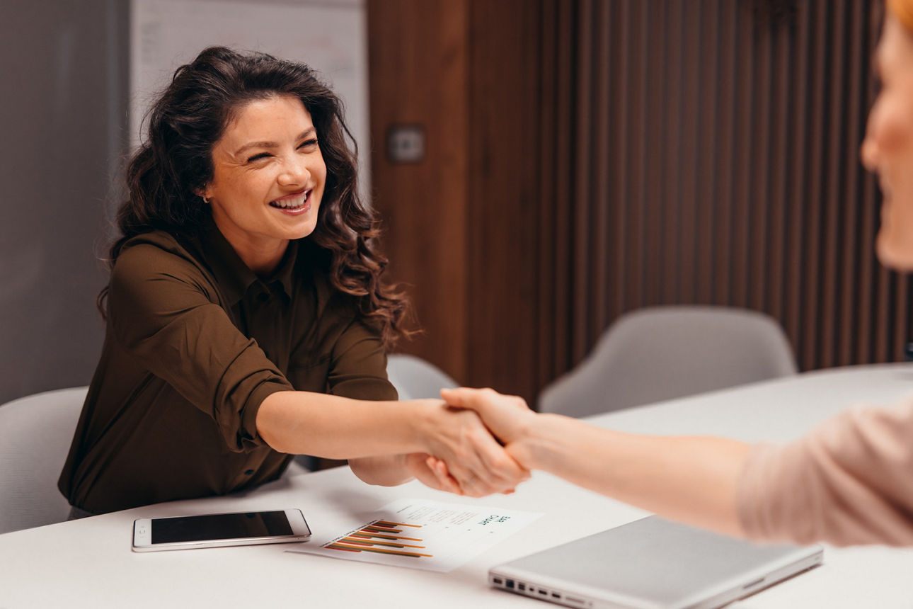 junge Frau im Beratungsgespräch gibt Beraterin die Hand