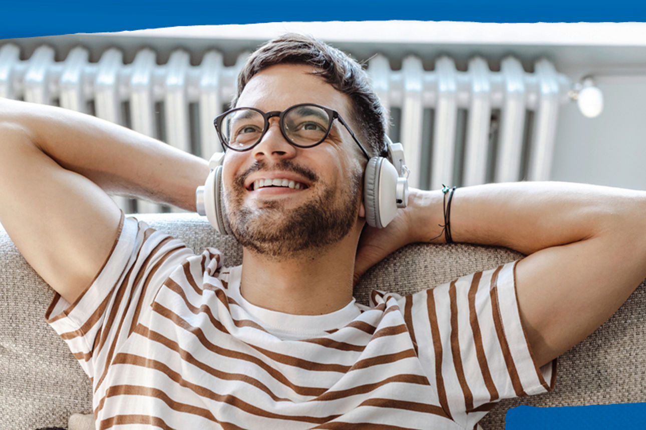 Mann liegt entspannt auf seiner Couch und hört Musik