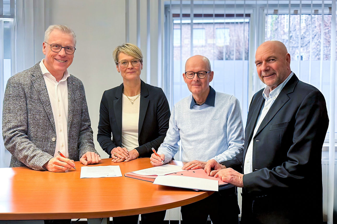 Vier Personen im Büro mit Tisch bei einer Vertragsunterzeichnung