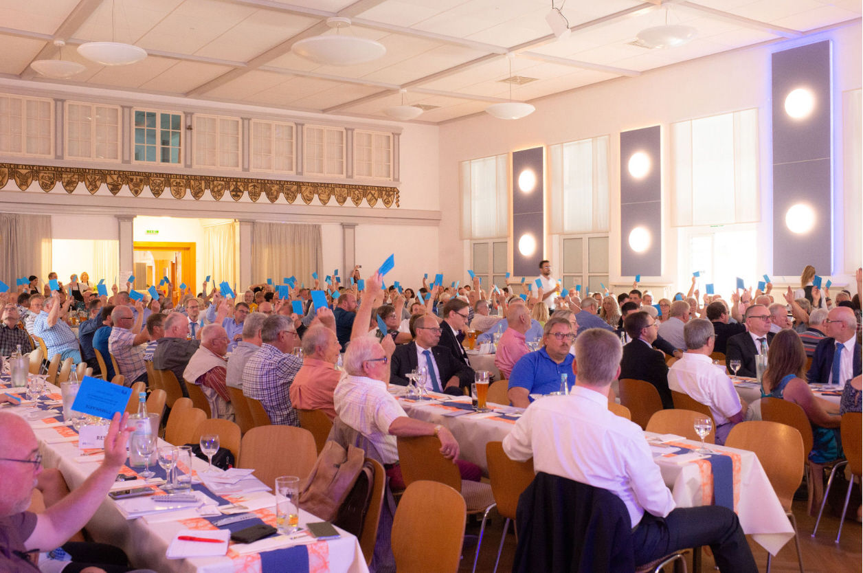 Eine große Gruppe von Menschen ist in einem Konferenzraum versammelt.