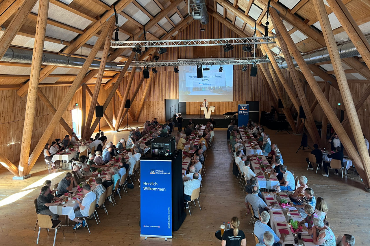 Raum während der Vertreterversammlung mit Tischen, Vertretern und Bühne mit Präsentation